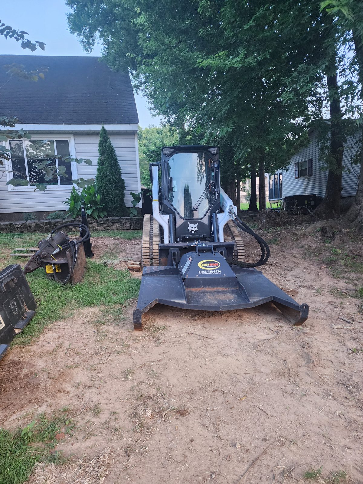 Bobcat T66 with heavy duty brush cutter mounted and the concrete breaker beside it