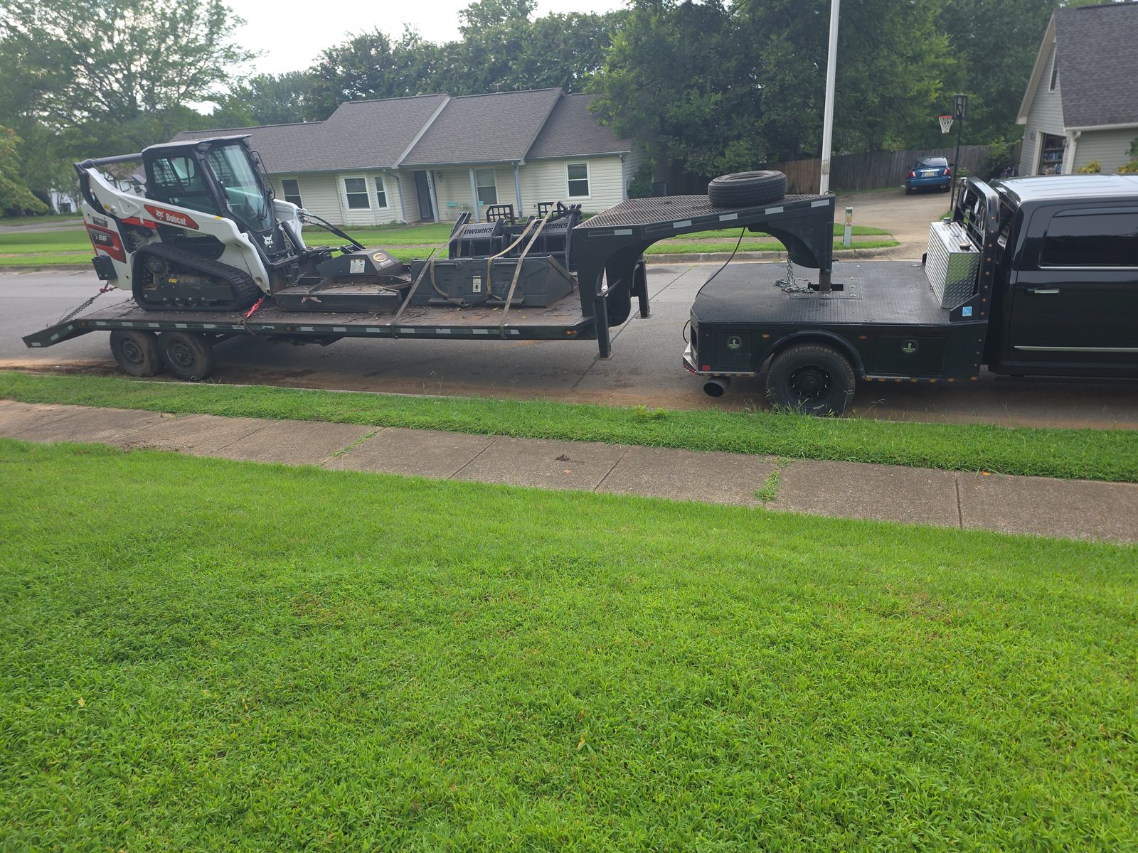 Bobcat T66 and attachments loaded on a gooseneck trailer behind a pickup truck